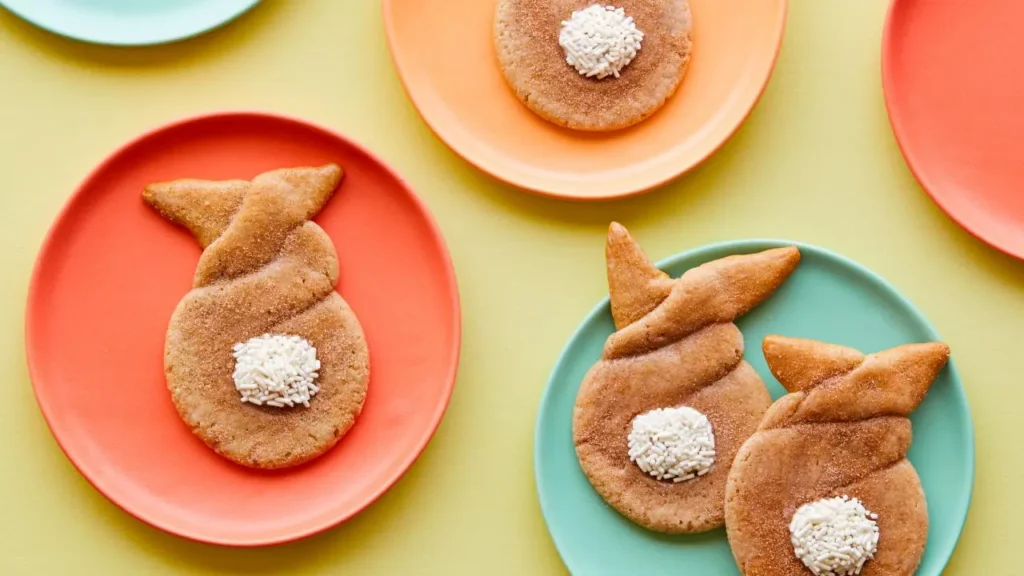 Twisted cinnamon sugar cookies shaped like bunnies with white sprinkle-coated marshmallow tails