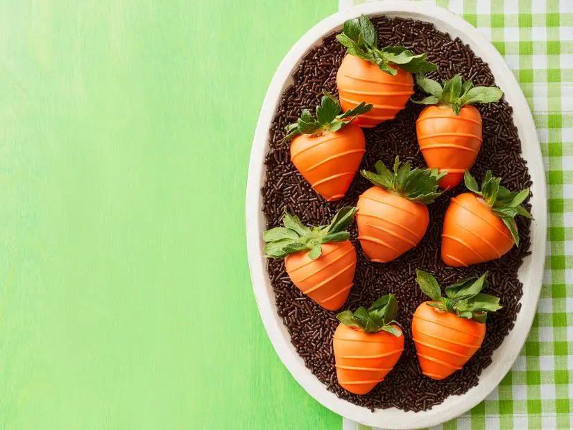 Plump strawberries coated in glossy orange candy melts with drizzled texture lines resembling carrots
